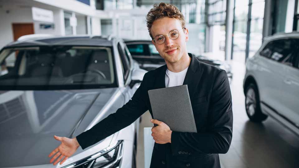 Ein Verkäufer zeigt auf ein Auto und erklärt dem Kunden die Konditionen beim Auto verkaufen Tübingen